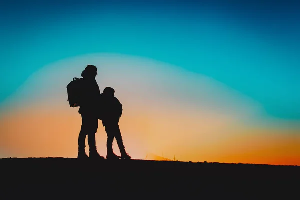 Силуэты отца и сына, путешествующие в горах заката — стоковое фото