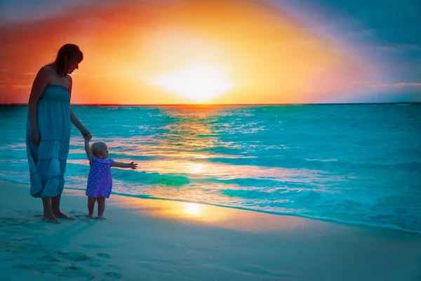 Mãe e pequena filha desfrutar do pôr do sol na praia — Fotografia de Stock