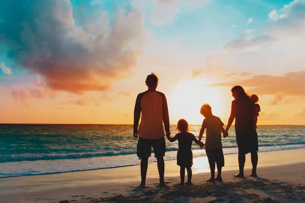 Família feliz com as crianças da árvore andam na praia do por do sol — Fotografia de Stock