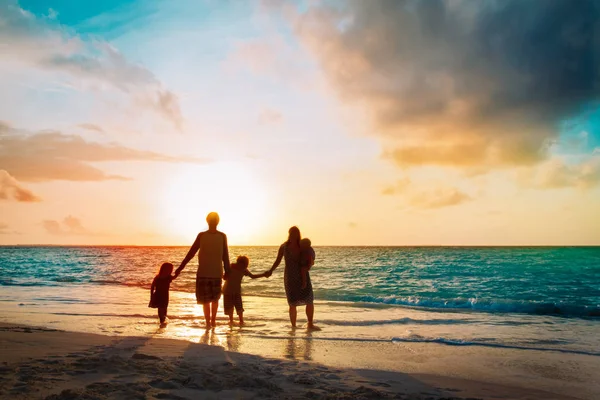 Famiglia felice con albero bambini passeggiata sulla spiaggia al tramonto — Foto Stock