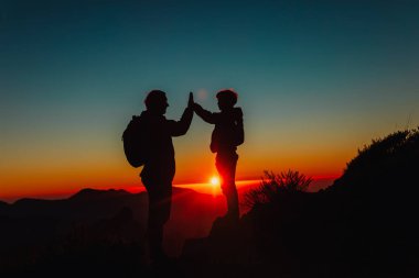Baba ve oğul gün batımı dağlarında seyahat ediyorlar.