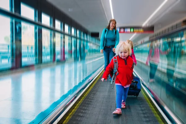 Familia en travalator en aeropuerto, niña con madre y hermana viajan juntos — Foto de Stock
