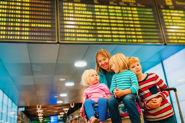Mamma med tre barn reser på flygplatsen, familjeresa — Stockfoto