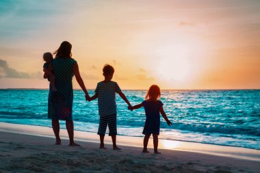 gün batımında sahilde yürüyüş üç çocuk annesi