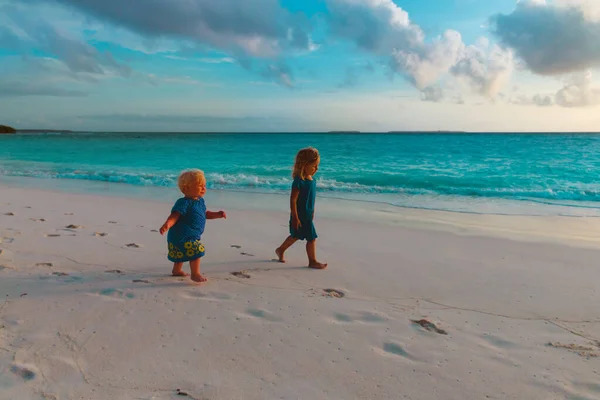 Feliz lindo niñas caminar en el atardecer tropical playa —  Fotos de Stock