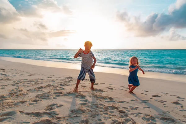 Šťastný malý chlapec a dívka hrát a tančit na pláži — Stock fotografie