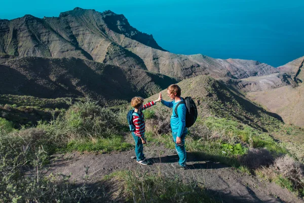 Glücklicher Vater und Sohn hoch fünf beim Wandern in den Bergen am Meer, Familie auf den Kanarischen Inseln — Stockfoto