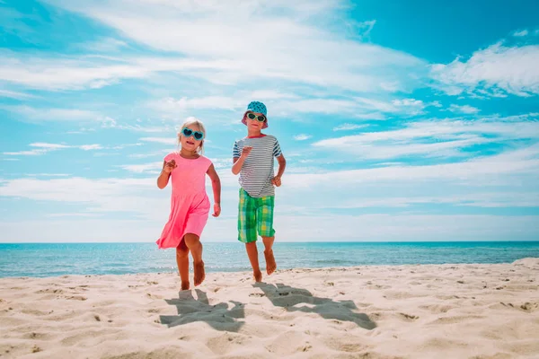 Счастливые симпатичные мальчик и девочка бегают по пляжу, дети наслаждаются отдыхом на море — стоковое фото
