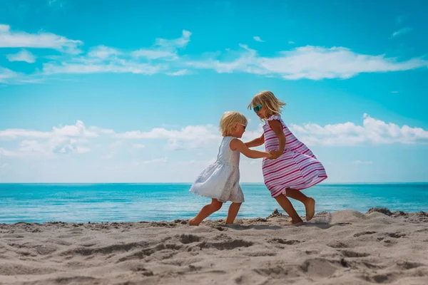 Güzel küçük kızlar sahilde dans eder, aile tropikal tatilin tadını çıkarır. — Stok fotoğraf