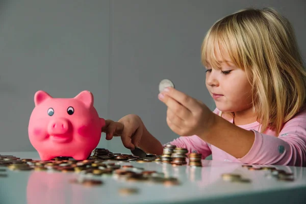 Дитина заощаджує гроші, мила дівчина кладе монети в скарбничку — стокове фото