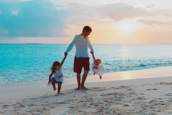 Отец с маленькими девочками играют на пляже заката, папа и дочери весело — стоковое фото
