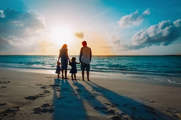 Glückliche Familie mit zwei Kindern spazieren am Strand von Sonnenuntergang — Stockfoto