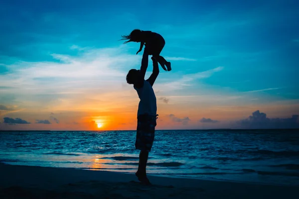 Père et petite fille silhouettes jouent à la plage coucher de soleil — Photo