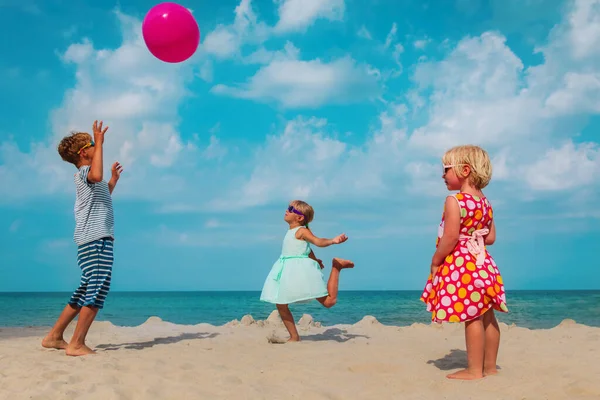 Děti - chlapec a dívky- hrát si s míčem na pláži dovolenou — Stock fotografie
