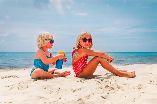 Защита от солнца - маленькие девочки с солнцезащитным кремом на пляже — стоковое фото