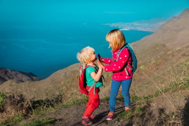 Mutlu küçük kızlar beşlik çakar deniz kenarındaki dağlarda dolaşır, aile yürüyüşü yapar
