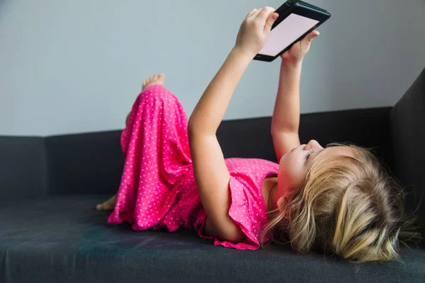 Mała dziewczynka czyta e-book zrelaksowany w domu — Zdjęcie stockowe