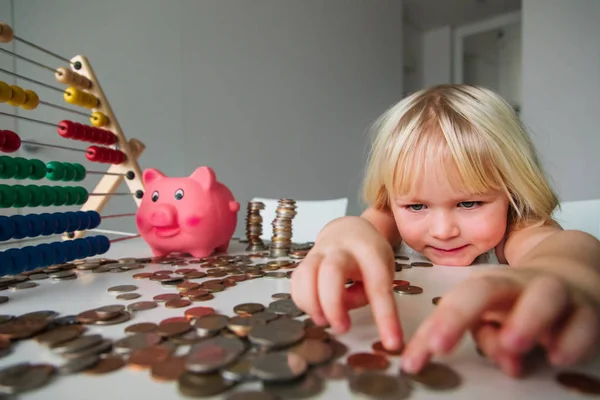 Дитина рахує монети і заощаджує гроші, мила дівчина кладе монети в скарбничку — стокове фото