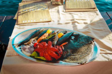 Denizdeki restoranda servis edilen taze deniz ürünleri tabağı.