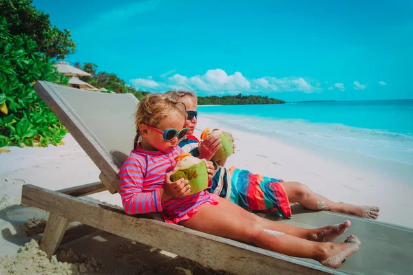 Malý chlapec a dívka pití kokosové na pláži — Stock fotografie