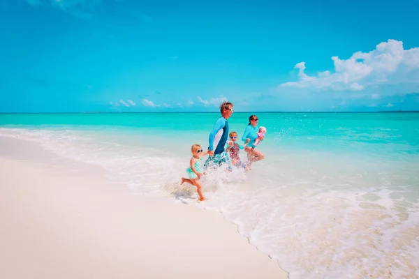 Šťastná rodinná hra s vodou, máma, táta s dětmi běh na pláži — Stock fotografie