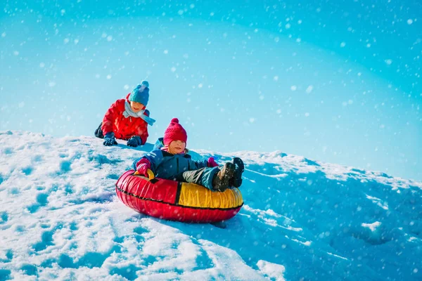 Menina bonito feliz e menino slide no inverno neve — Fotografia de Stock