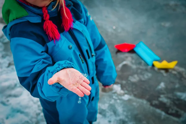 Niño sosteniendo hielo en las manos, jugando con barcos de papel en primavera — Foto de Stock