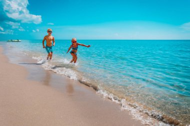 Mutlu kız ve oğlan koşun ve sahilde suyla oynayın