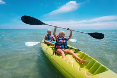 Mutlu kız ve oğlan sahilde kayak yapıyor.