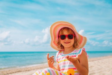 Güneş koruması. Kumsalda kremalı tatlı mutlu kız.