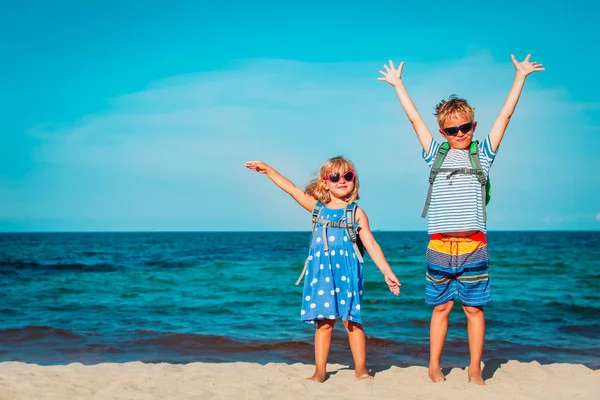 Счастливые дети с рюкзаками наслаждаются путешествиями по пляжу — стоковое фото
