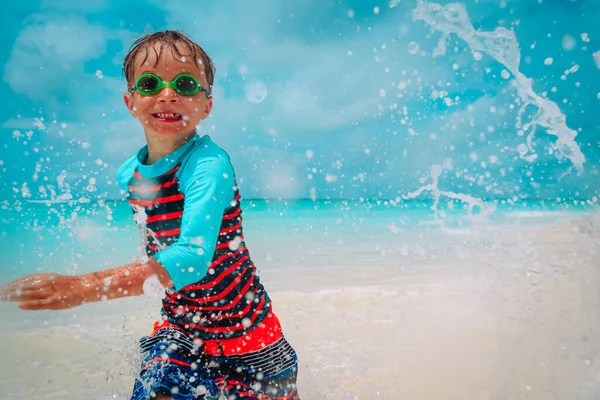 Felice carino ragazzo correre e spruzzare acqua sulla spiaggia — Foto Stock