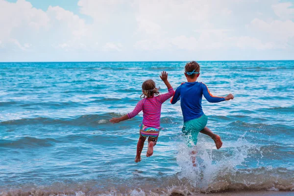 Kinderen - meisje en jongens- rennen en springen in het water op het strand — Stockfoto