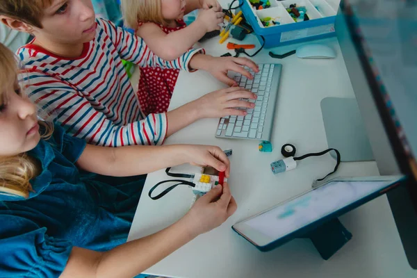 Niños construyendo robot y programándolo con almohadilla táctil y computadora —  Fotos de Stock