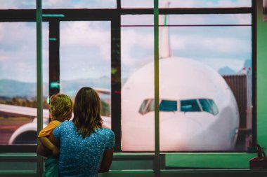 Anne ve küçük oğlu havaalanında uçağa bakıyorlar.
