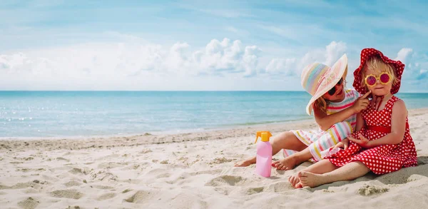 Protección solar - niñas con crema solar en la playa —  Fotos de Stock