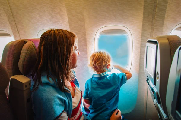 Madre e hijo pequeño viajan en avión, familia en vuelo — Foto de Stock