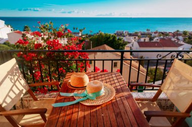 Balkon terasında deniz manzaralı iki şapka, seyahat konsepti.