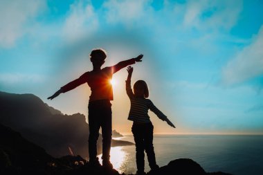 happy boy and girl travel in mountains near sea at sunset