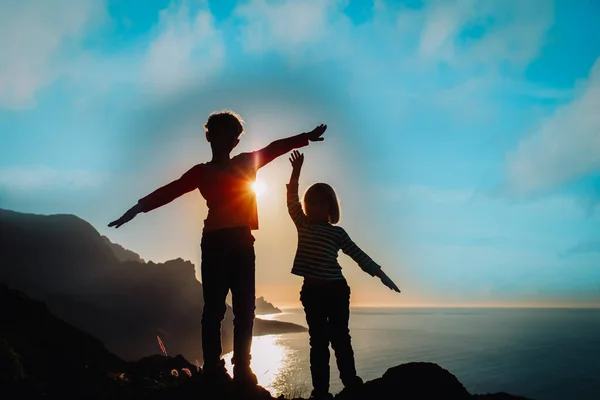 Happy boy and girl travel in mountains near sea at sunset — Zdjęcie stockowe