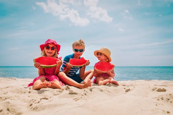 Счастливые милые дети едят арбуз на пляже — стоковое фото