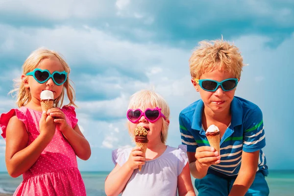 Enfants heureux- garçon et filles- manger de la crème glacée sur la plage — Photo