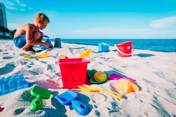 Kinderen speelgoed en jongen gebouw kasteel op het strand — Stockfoto