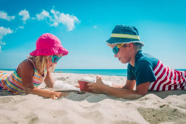Chlapec a dívka číst knihy na pláži, rodinná dovolená — Stock fotografie