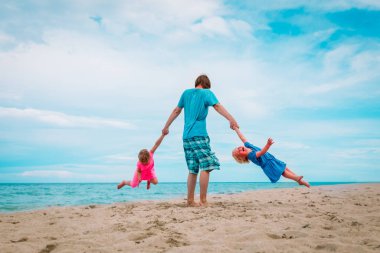 Çocuklu baba plaj tatilinde oynuyor.