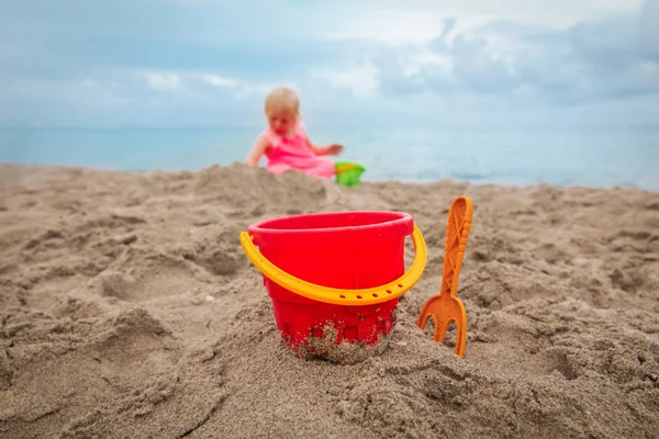 Giocattoli di sabbia e bambina che gioca in vacanza al mare — Foto Stock