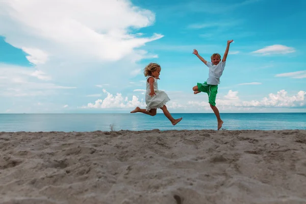 Mutlu erkek ve kız kumsalın tadını çıkarır, çocuklar denizde oynar. — Stok fotoğraf