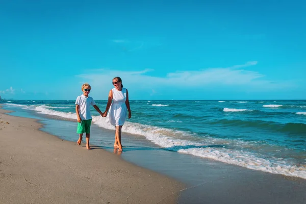Gelukkig moeder met zoon lopen op het strand, familie op zee — Stockfoto