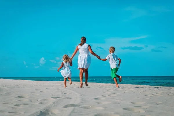 Moeder met kinderen spelen, familie gerund op tropische strand — Stockfoto