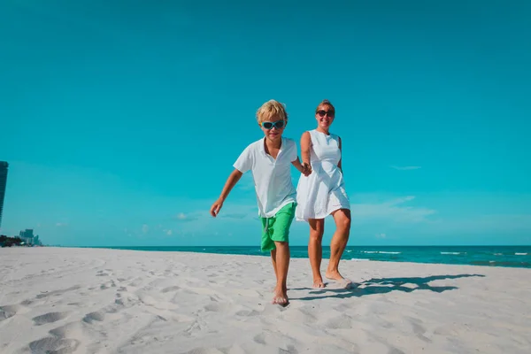 Gelukkig moeder met zoon lopen op het strand, familie op zee — Stockfoto